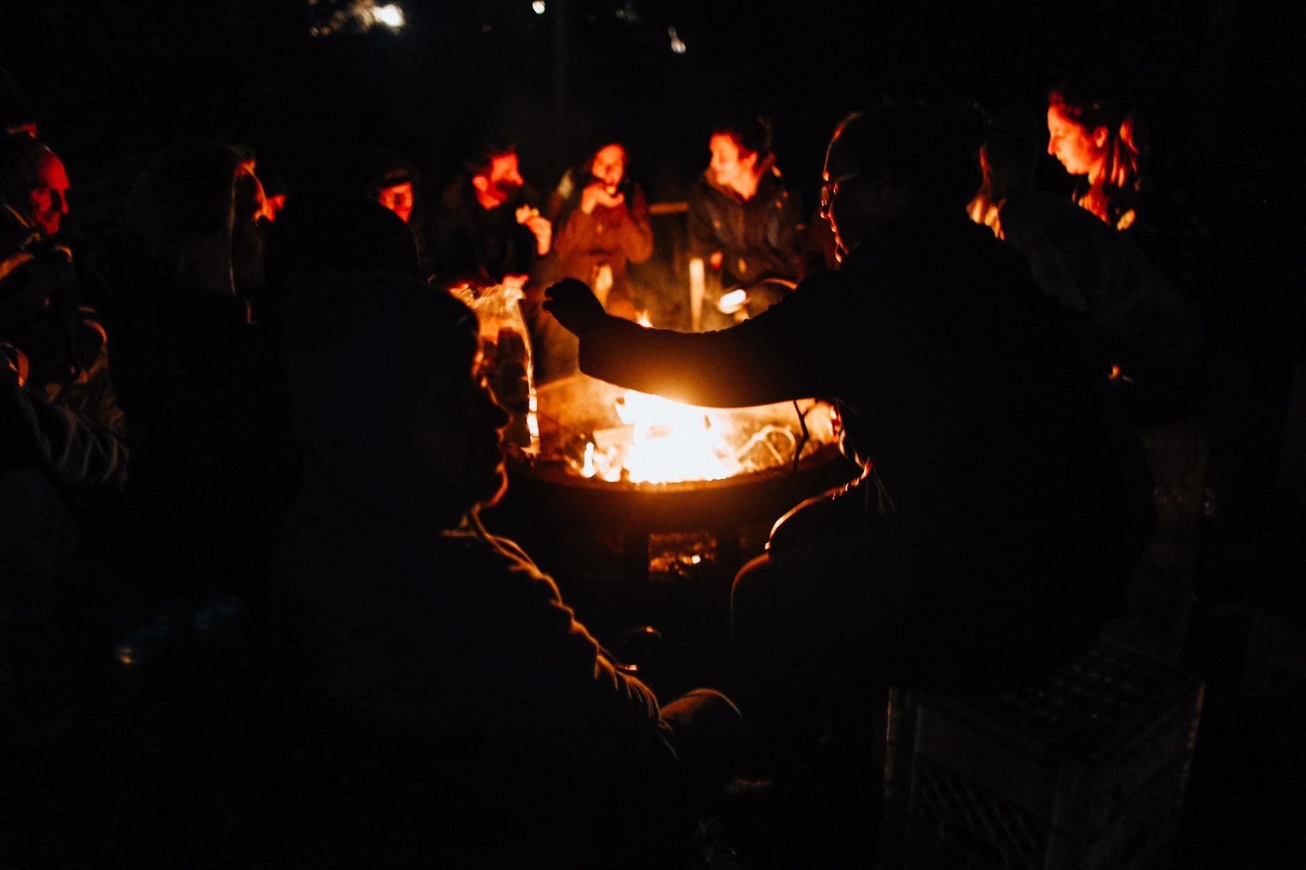 A warm group enjoying a nighttime bonfire outdoors with friends